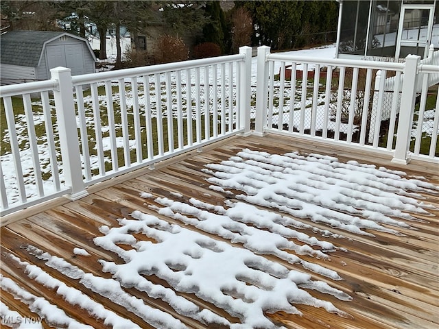 snow covered deck with a storage shed