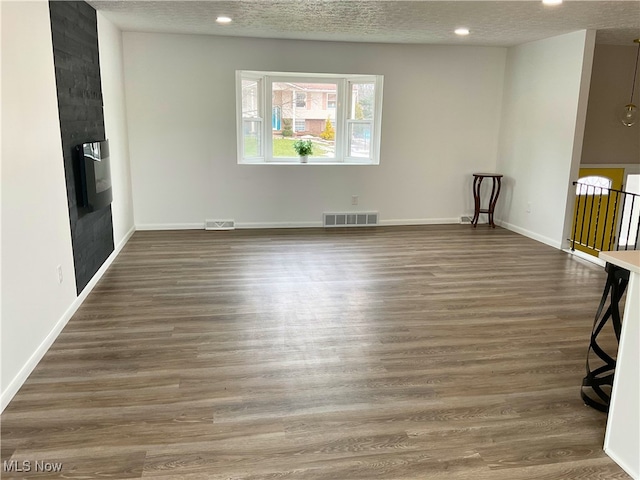 spare room featuring a large fireplace, dark hardwood / wood-style floors, and a textured ceiling