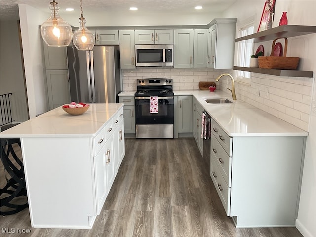 kitchen with appliances with stainless steel finishes, dark hardwood / wood-style floors, sink, hanging light fixtures, and a center island