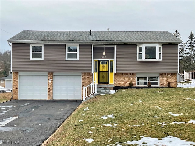 bi-level home featuring a garage and a front lawn