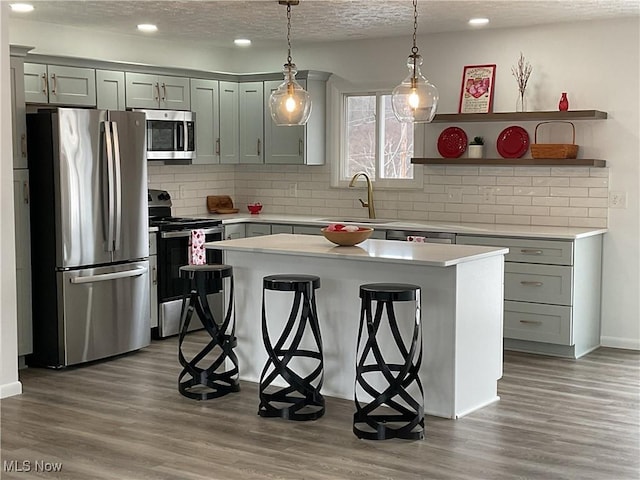 kitchen with pendant lighting, sink, a breakfast bar area, stainless steel appliances, and a kitchen island