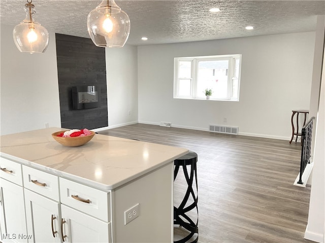 kitchen featuring light wood-style floors, visible vents, a large fireplace, and a textured ceiling