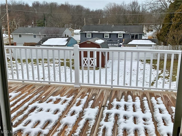 snow covered deck with a storage shed