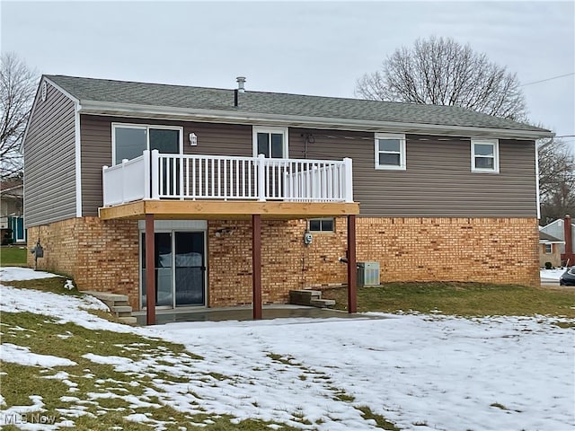 snow covered house featuring a balcony and central AC unit