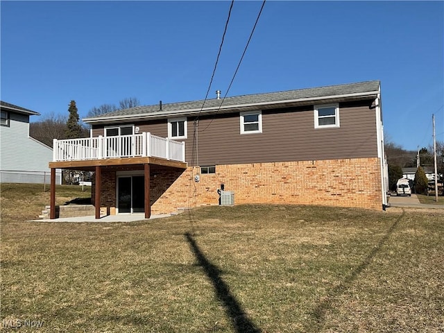 back of property featuring a deck, a yard, cooling unit, brick siding, and a patio area