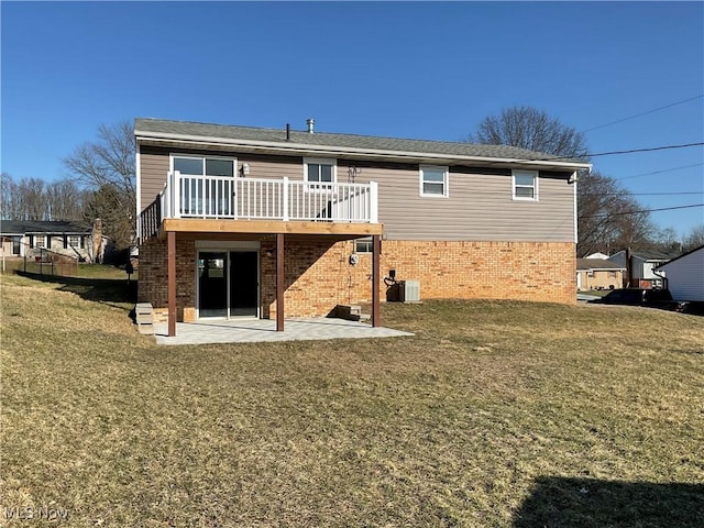 rear view of property with a yard, a patio, brick siding, and a wooden deck