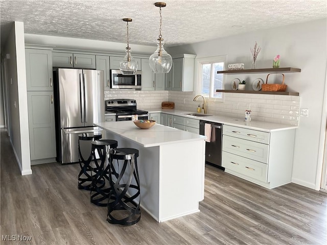 kitchen featuring wood finished floors, stainless steel appliances, light countertops, and a sink