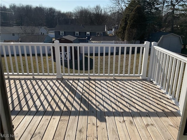 deck featuring an outbuilding, a yard, a fenced backyard, a storage unit, and a residential view