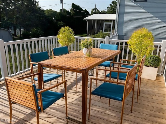 wooden terrace featuring outdoor dining space and a sunroom