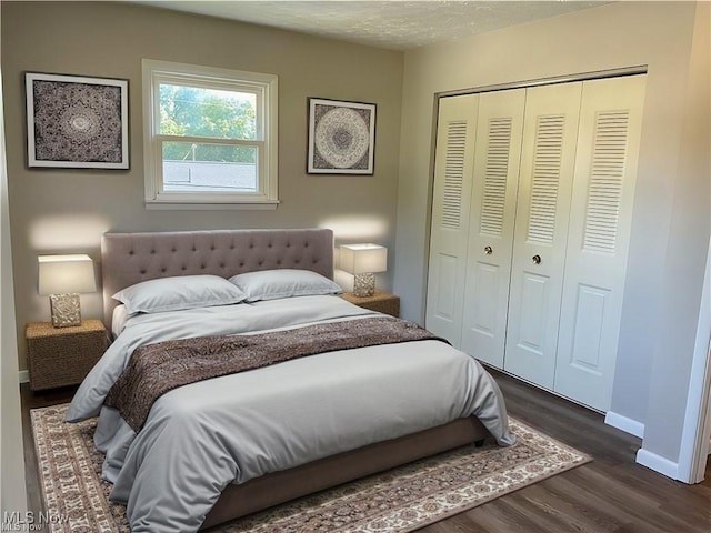 bedroom featuring a textured ceiling, dark wood-style floors, a closet, and baseboards