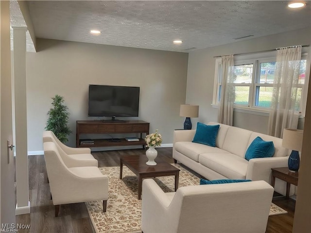 living room with recessed lighting, wood finished floors, baseboards, and a textured ceiling