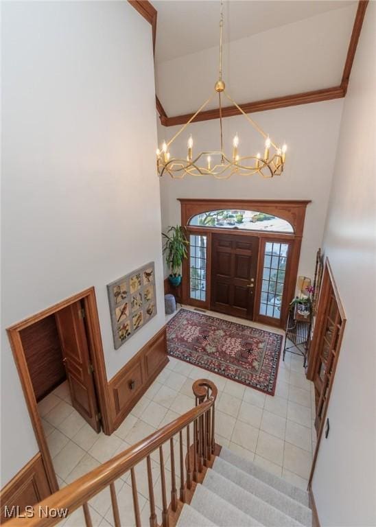 foyer entrance featuring light tile patterned flooring, a notable chandelier, and high vaulted ceiling