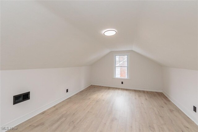 additional living space with vaulted ceiling and light hardwood / wood-style floors