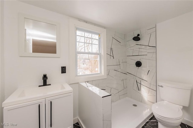 bathroom with vanity, toilet, and a tile shower