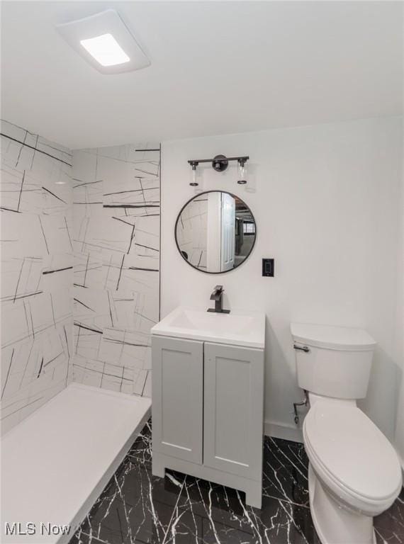 bathroom featuring vanity, tiled shower, and toilet