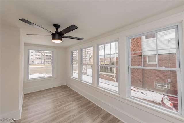 unfurnished sunroom with ceiling fan