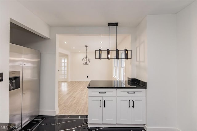 kitchen featuring dark wood-type flooring, stainless steel refrigerator with ice dispenser, hanging light fixtures, and white cabinets