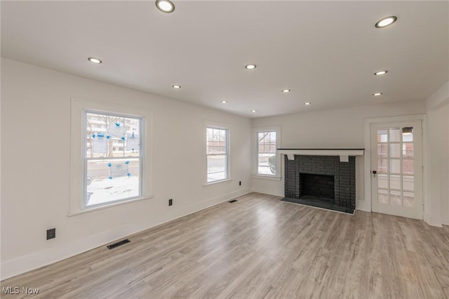 unfurnished living room featuring a brick fireplace and light hardwood / wood-style floors