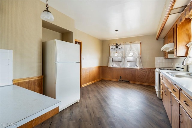 kitchen with dark hardwood / wood-style flooring, white appliances, decorative light fixtures, and an inviting chandelier