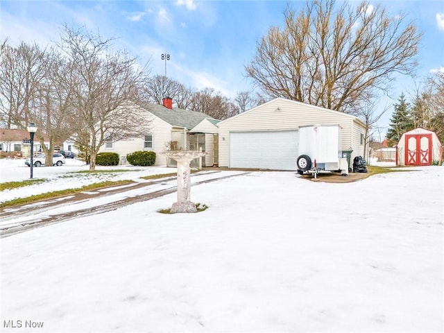 snow covered property featuring a garage and a storage unit