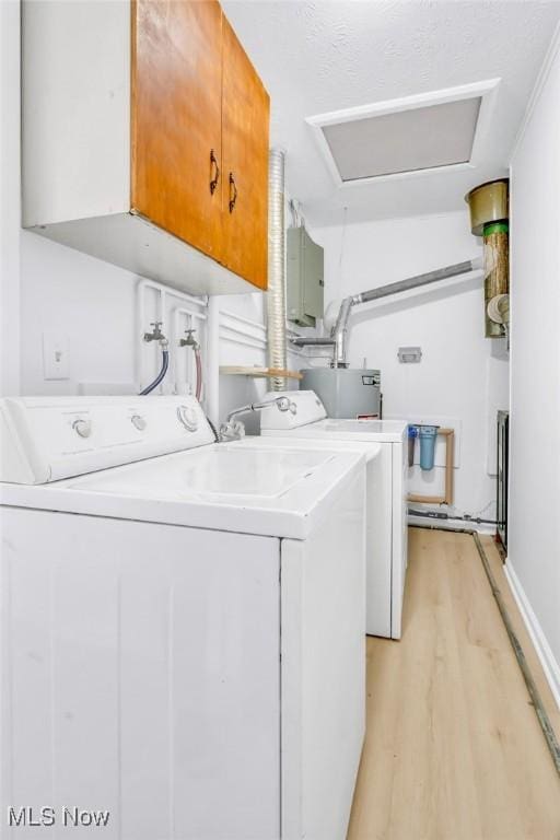 washroom with independent washer and dryer, cabinets, water heater, and light wood-type flooring