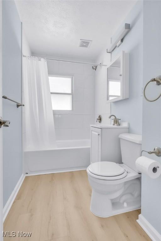 bathroom with hardwood / wood-style floors, shower / bathtub combination with curtain, and toilet