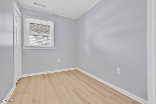 spare room featuring crown molding and light wood-type flooring