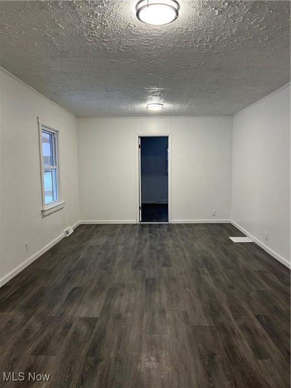 empty room featuring dark hardwood / wood-style floors and a textured ceiling