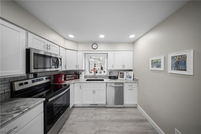 kitchen featuring light stone counters, sink, white cabinets, and appliances with stainless steel finishes