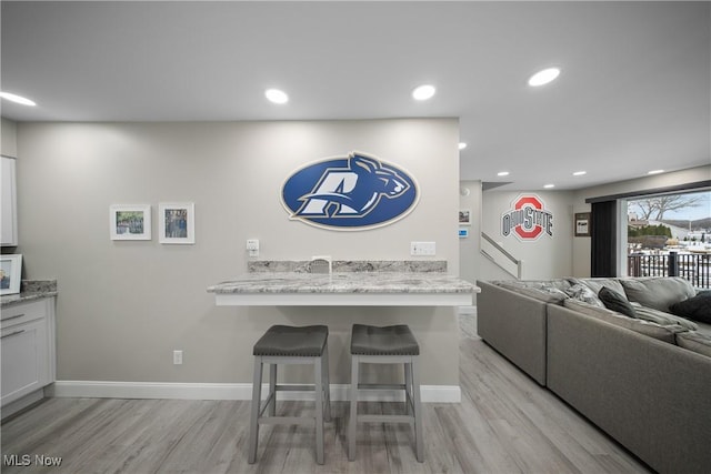 interior space with a breakfast bar, light hardwood / wood-style floors, kitchen peninsula, and white cabinets