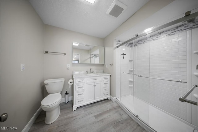 bathroom with vanity, an enclosed shower, wood-type flooring, a textured ceiling, and toilet