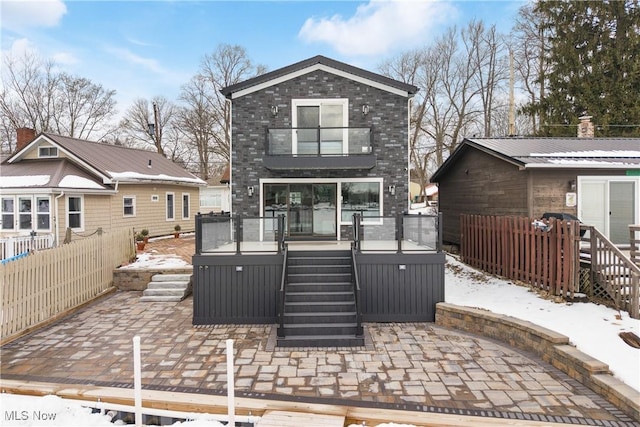 snow covered house featuring a patio area