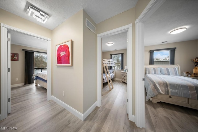 corridor with plenty of natural light, light hardwood / wood-style floors, and a textured ceiling