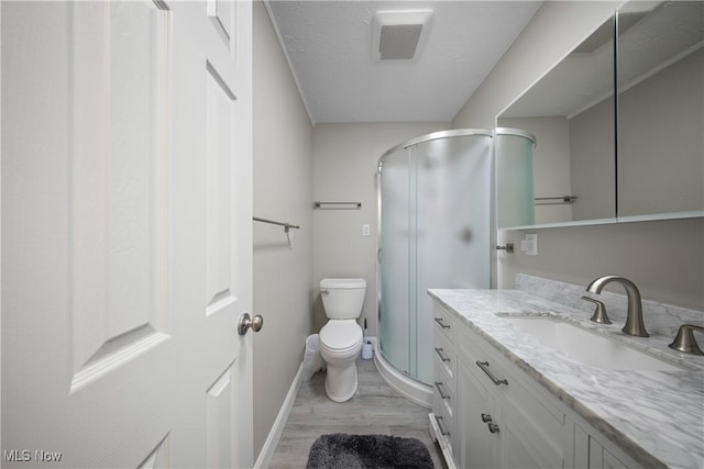 bathroom with hardwood / wood-style flooring, vanity, toilet, and a shower with shower door