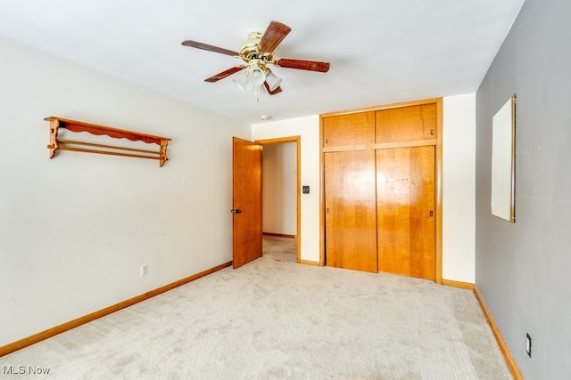 unfurnished bedroom featuring ceiling fan, a closet, and light carpet