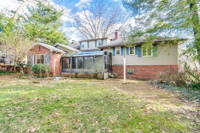 back of property with a sunroom and a lawn