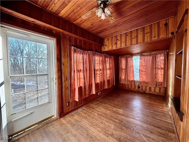 interior space featuring hardwood / wood-style flooring, ceiling fan, wood ceiling, and wooden walls