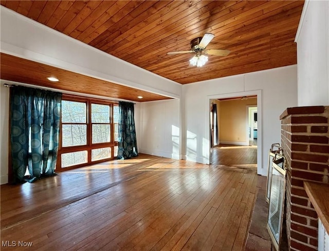 interior space featuring wood ceiling, hardwood / wood-style flooring, a brick fireplace, and ceiling fan