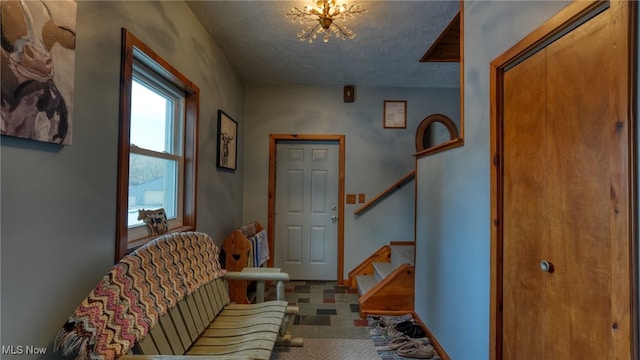 foyer entrance with a chandelier and a textured ceiling