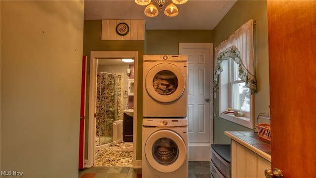 washroom featuring stacked washer and dryer and a notable chandelier