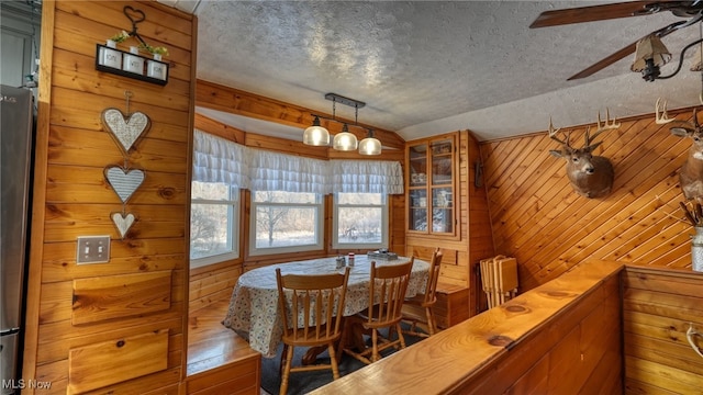 2250 Indian Camp Run Rd, New Concord, OH 43762 - dining space featuring a textured ceiling, a ceiling fan, wood finished floors, lofted ceiling, and wooden walls