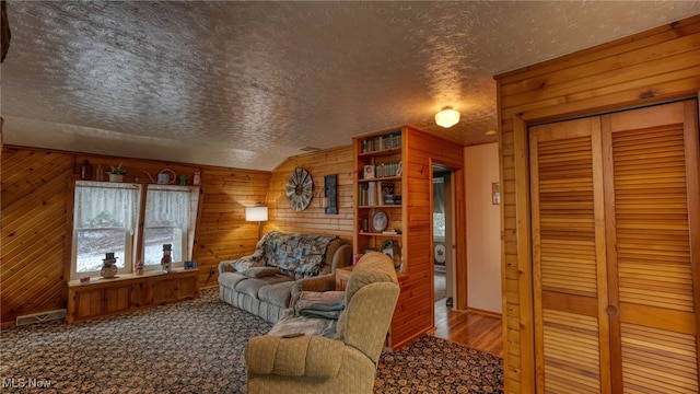 living room with wood-type flooring, vaulted ceiling, wooden walls, and a textured ceiling