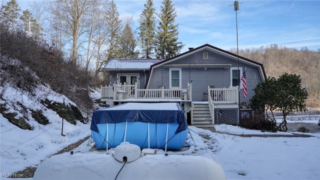 snow covered rear of property featuring a swimming pool side deck