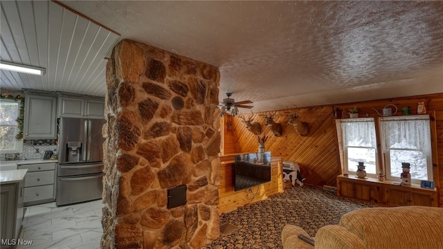 interior space with ceiling fan, a textured ceiling, and wood walls