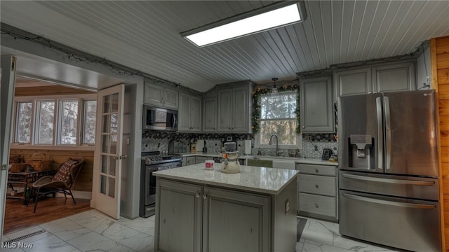 kitchen featuring a kitchen island, appliances with stainless steel finishes, sink, and decorative backsplash