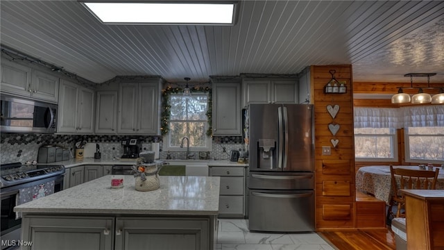 kitchen with stainless steel appliances, a center island, and gray cabinetry