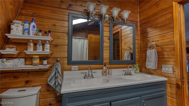 bathroom with wooden walls, vanity, toilet, and a notable chandelier