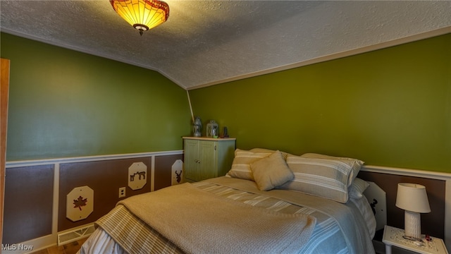 2250 Indian Camp Run Rd, New Concord, OH 43762 - bedroom featuring visible vents, a wainscoted wall, vaulted ceiling, and a textured ceiling