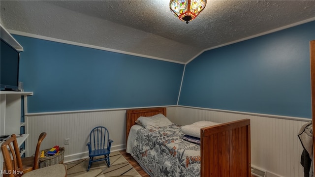 bedroom with hardwood / wood-style flooring, vaulted ceiling, and a textured ceiling