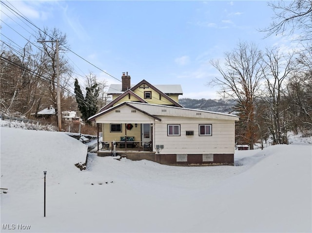 snow covered back of property with a porch